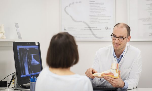 Dr. med. Benjamin Breuer, Departmentleiter Fußchirurgie, mit einer Patientin in der Sprechstunde (Foto: Kaiserswerther Diakonie/B. Engel-Albustin)