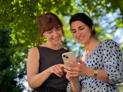 Zwei Frauen schauen sich Instagram auf dem Handy an.