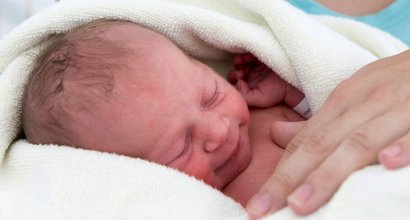 Neugeborenes Kind ist in ein Handtuch eingewickelt und schläft.