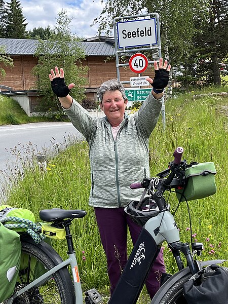 Eine Frau in Fahrradkleidung mit Fahrrad vor dem Verkehrsschild „Seefeld“