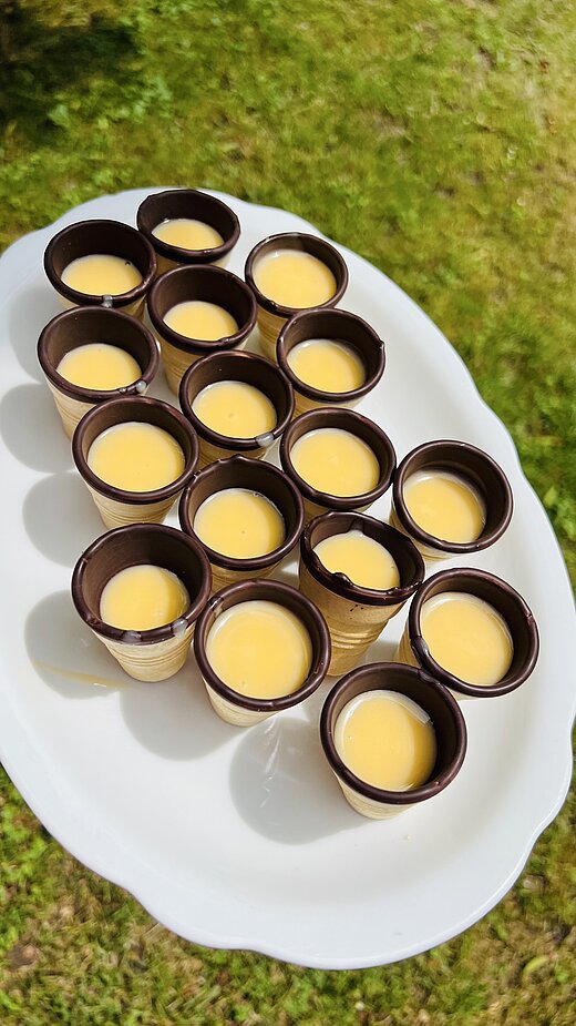 Ein Bild mit vielen kleinen Essbaren Waffelbechern, gefüllt mit Eierlikör.