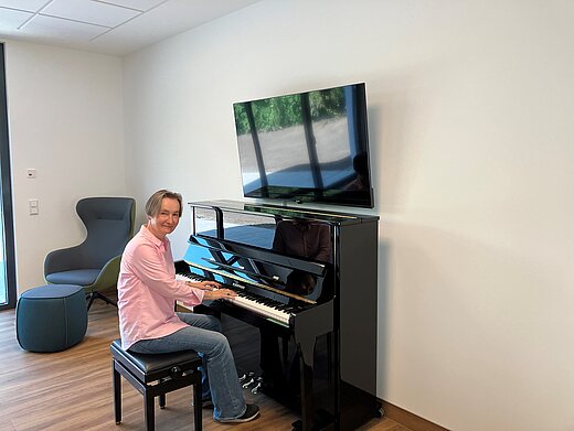 Eine Frau sitzt an einem Klavier. Ihre Hände liegen auf den Tasten