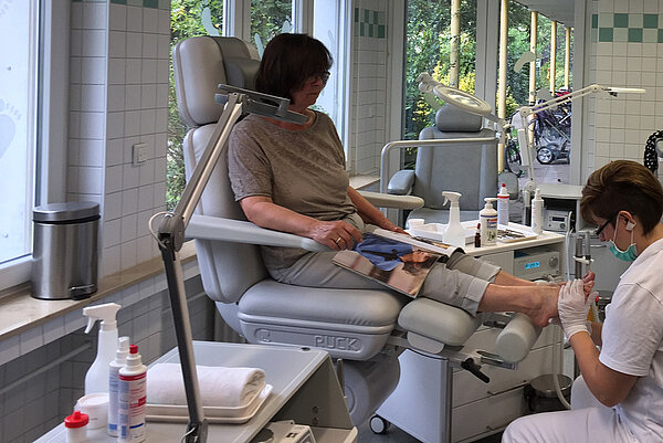 Eine Frau behandelt die Füße einer Patientin
