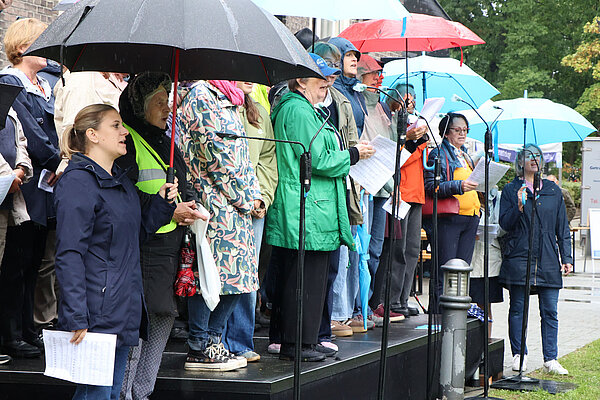 Der Chor mit Regenschirmen