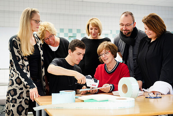 Lerngruppe mit sieben Personen an einem Tisch mit Material